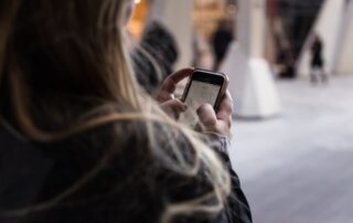 A woman looking at her cell phone while walking on a busy street.